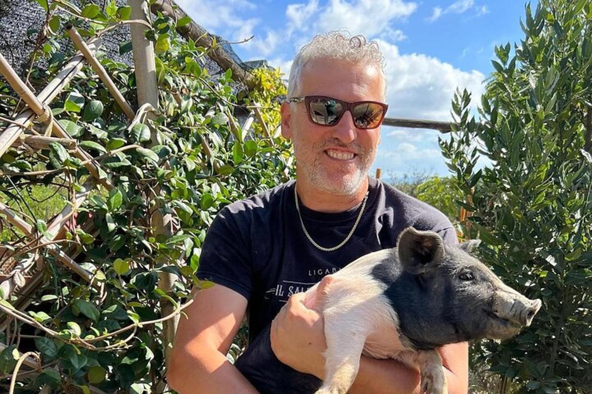 un uomo con occhiali da sole che tiene in braccio un cagnolino