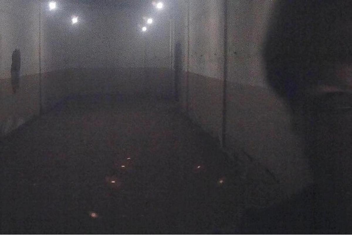 um quarto escuro com uma pessoa parada em um corredor