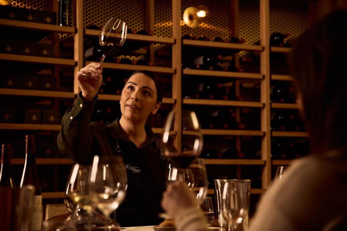 a man sitting at a table holding up a wine glass