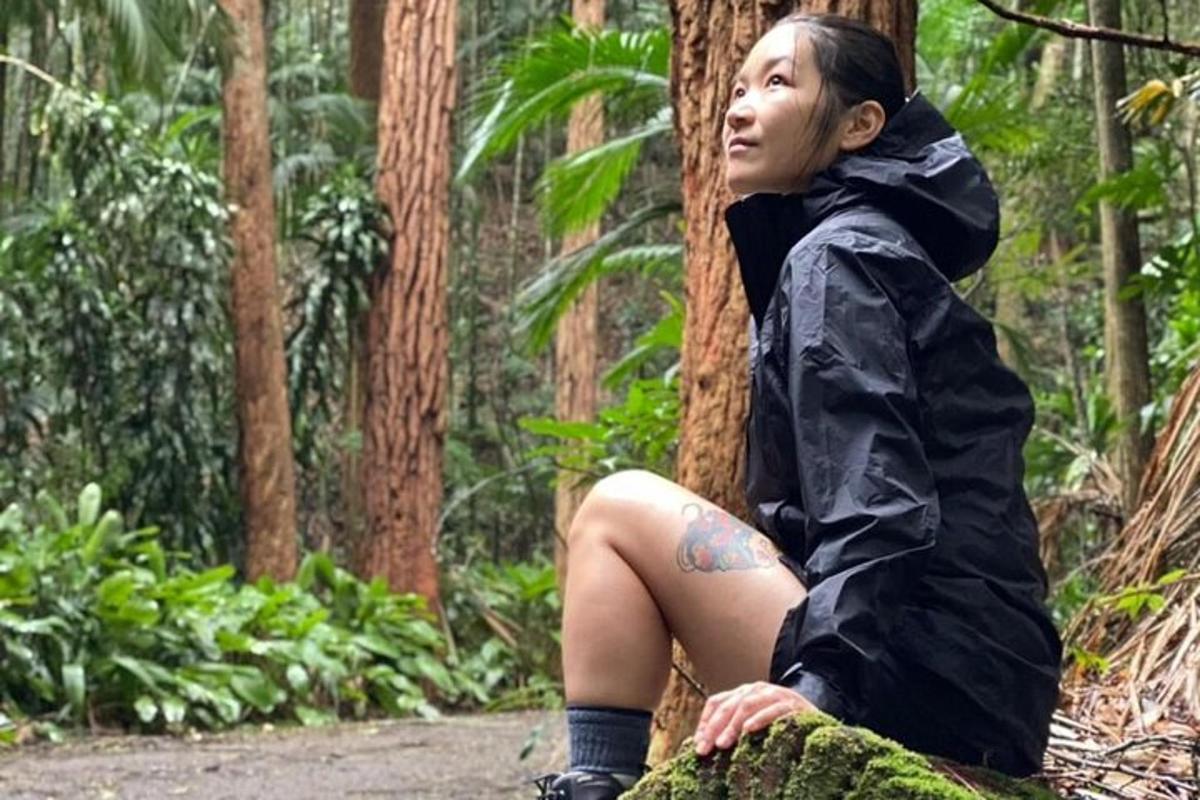 seorang wanita duduk di sebelah pokok dengan baju hujan