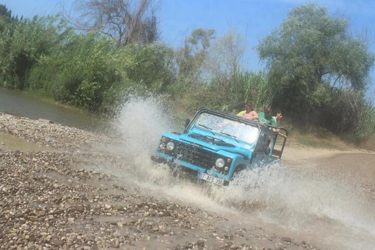 una jeep blu che attraversa un fiume con delle persone a bordo