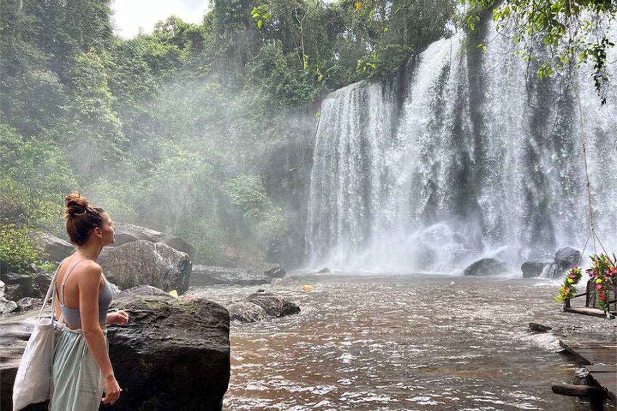 seorang wanita berdiri di depan air terjun