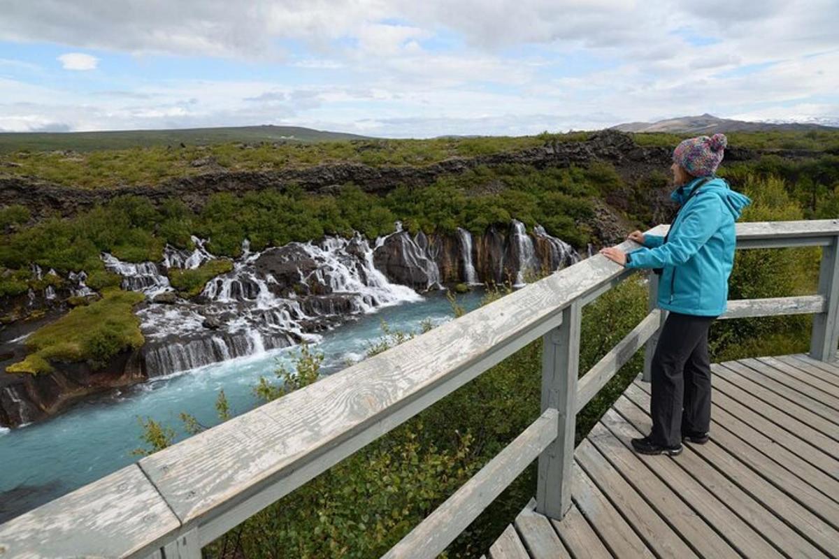 una donna in piedi su una passerella che guarda una cascata