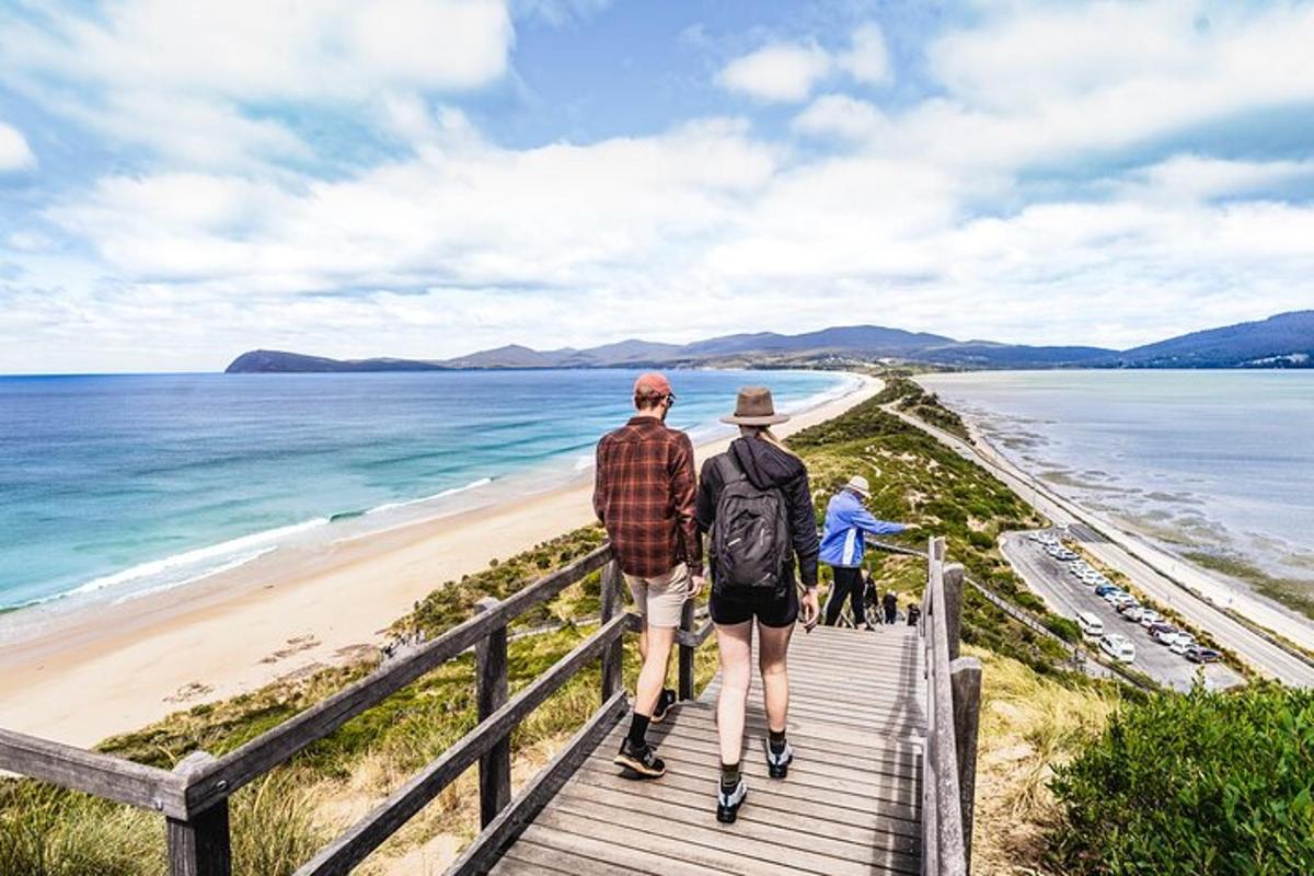 two people walking down a boardwalk to the beach