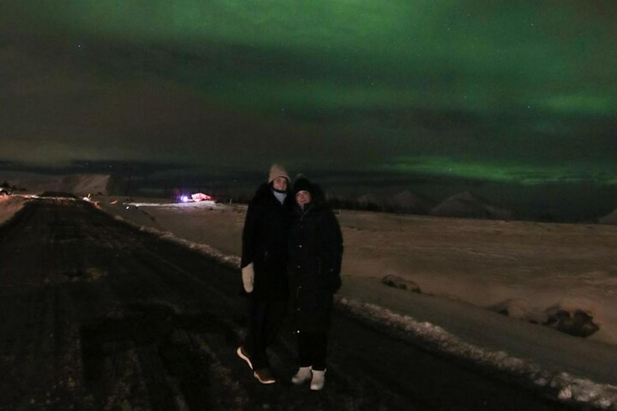 Dos personas están de pie en una pared por la noche.