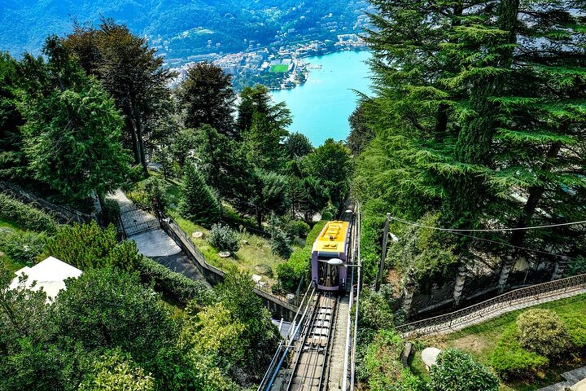 a yellow train traveling down the tracks near a lake