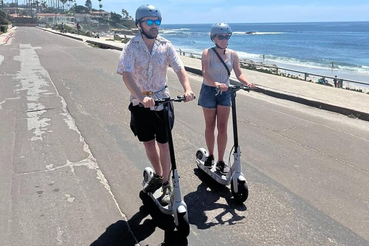 a man and woman riding scooters on the beach
