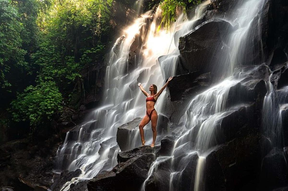 una donna in piedi su una roccia accanto a una cascata