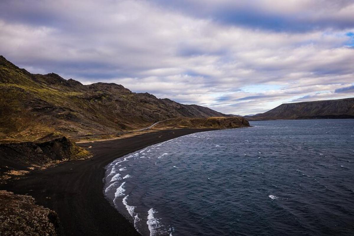 a black beach with the ocean and mountains