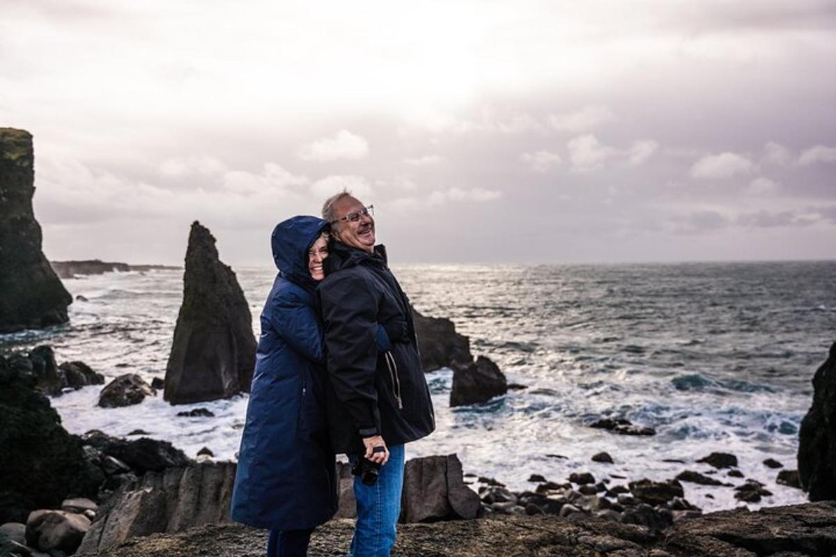 a man and woman standing on the rocks near the ocean