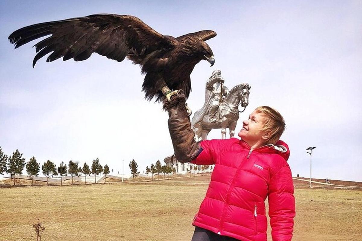 a woman holding a bird in front of a statue