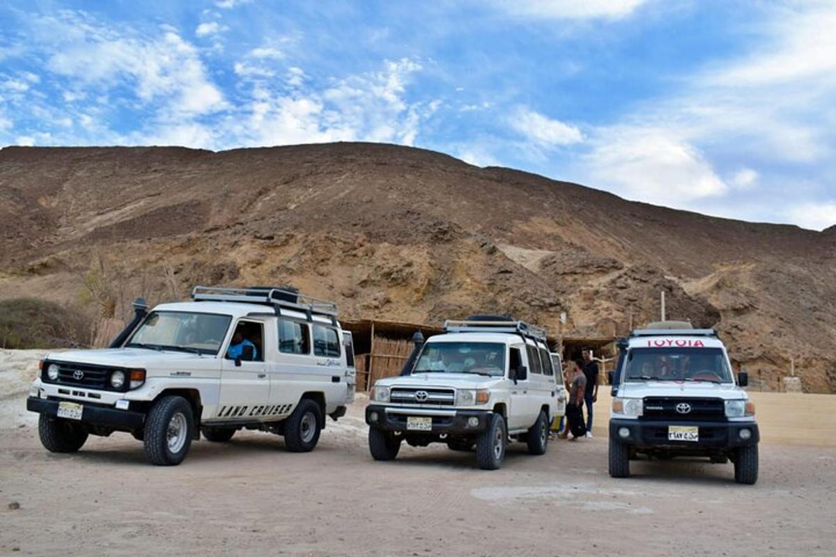 two white trucks parked in front of a mountain