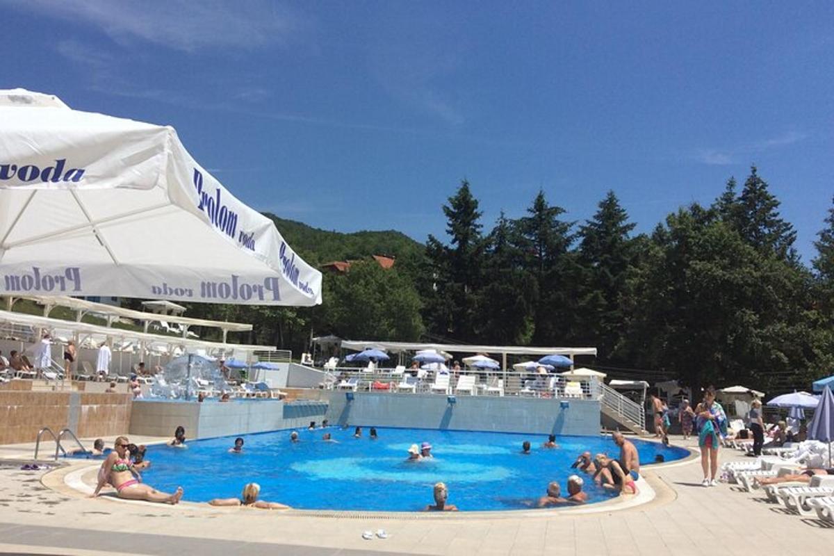 a group of people in a swimming pool with an umbrella