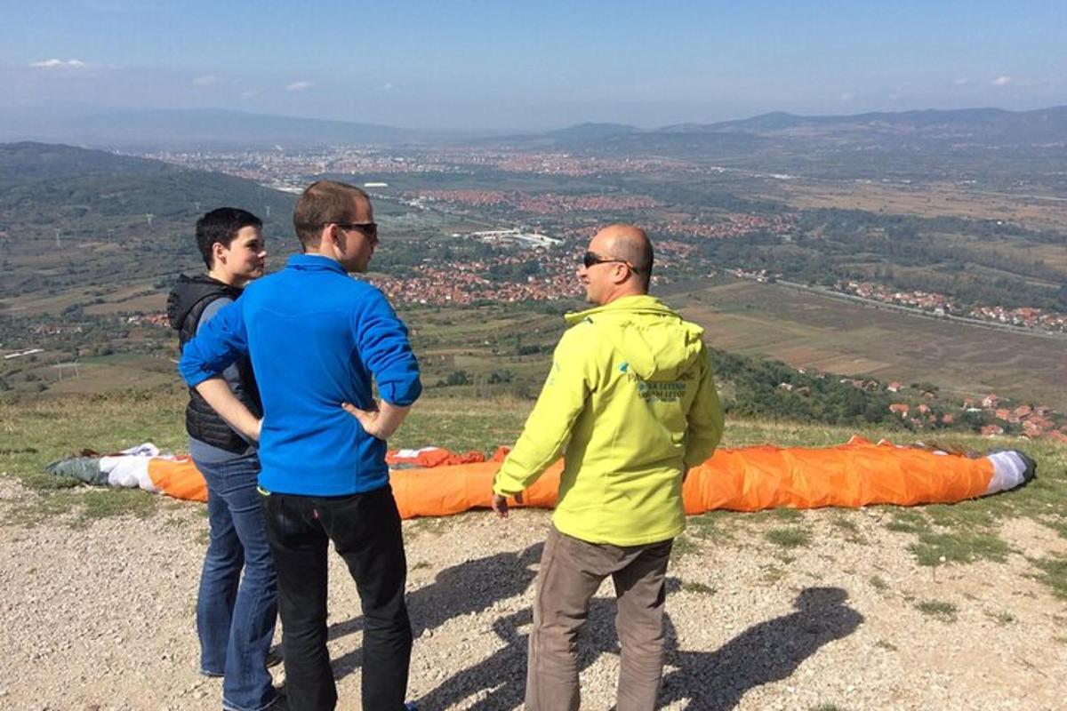 three men standing on top of a hill with a large parachute