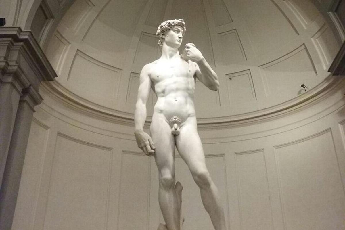 Una estatua de un hombre desnudo de pie en una habitación.