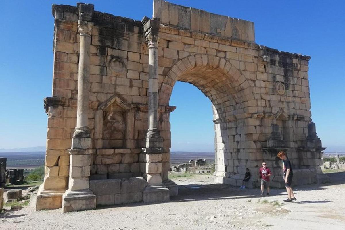 two people standing in front of a stone arch