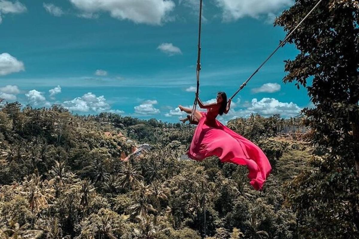 una donna con un vestito rosso che si dondola su un'altalena di corda