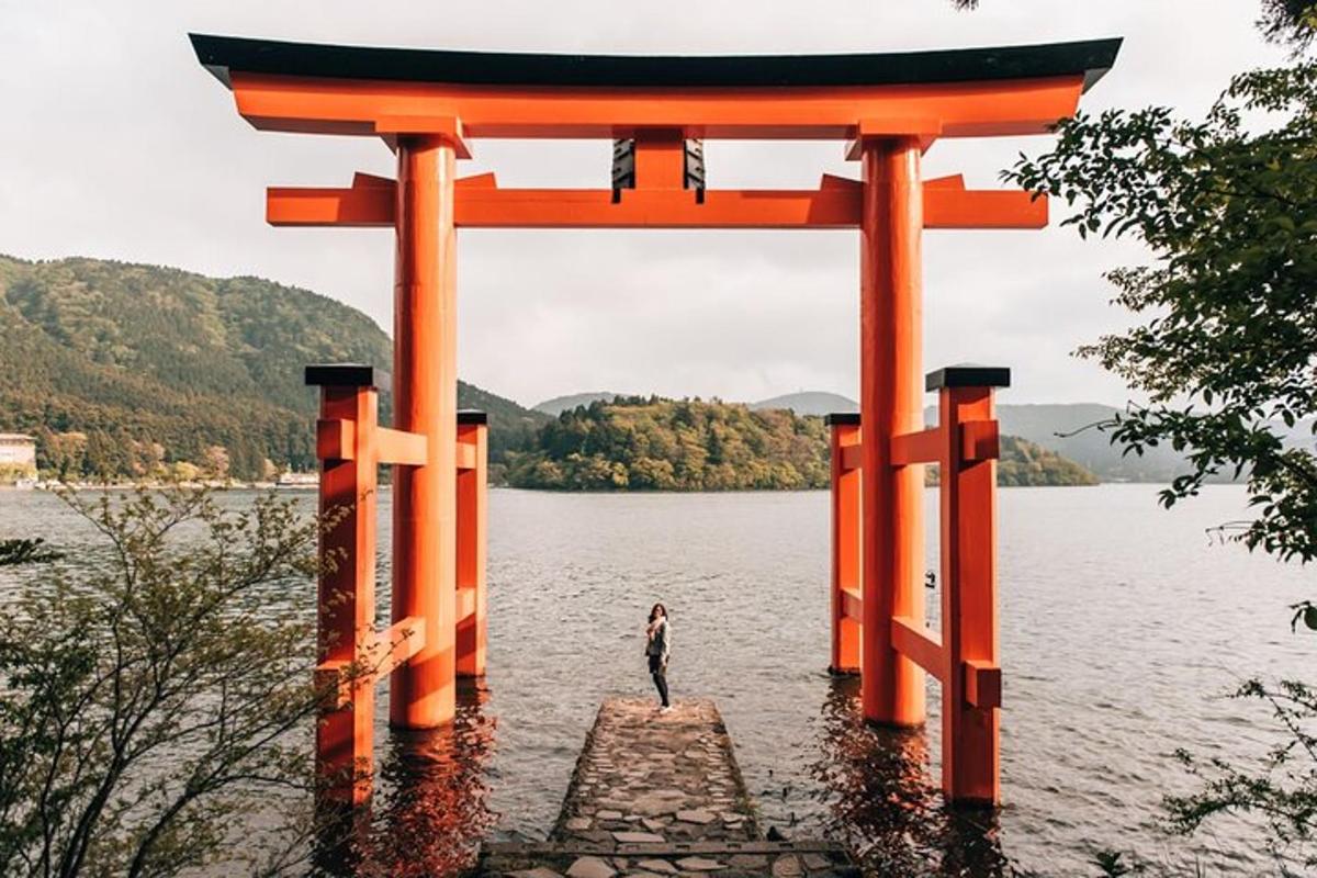 turuncu torii kapısının altında suda duran bir kişi