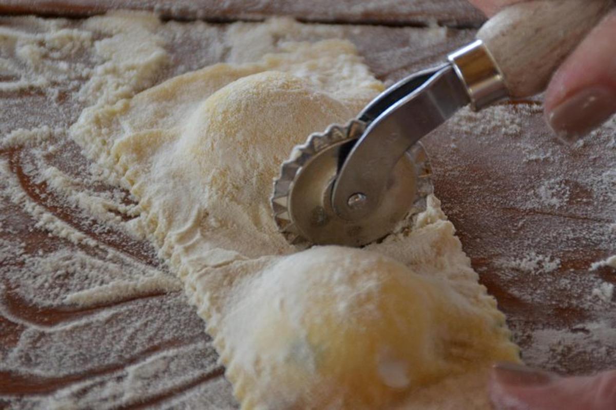 людина, яка використовує різак для тіста, щоб вирізати шматок тіста