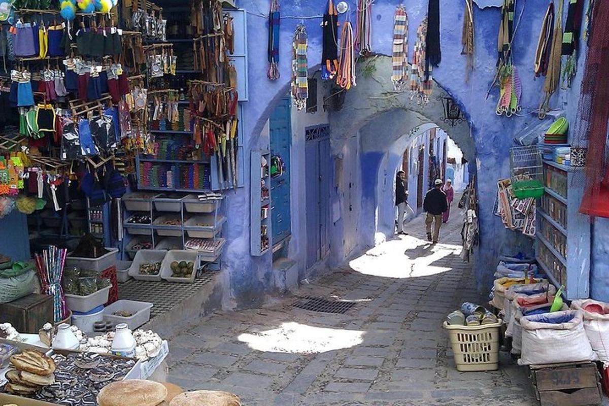 un vicolo con un edificio blu e persone che lo attraversano