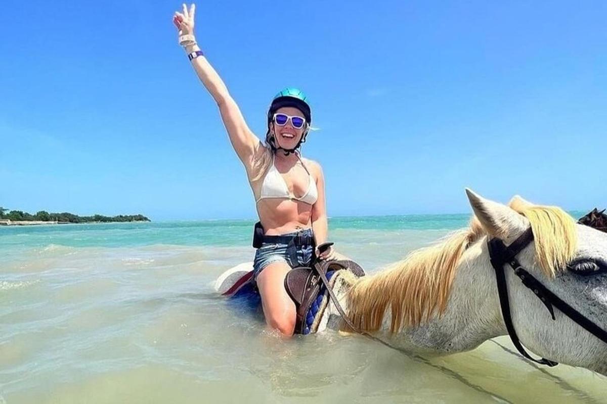 žena v bikinách jedoucí na koni v oceánu