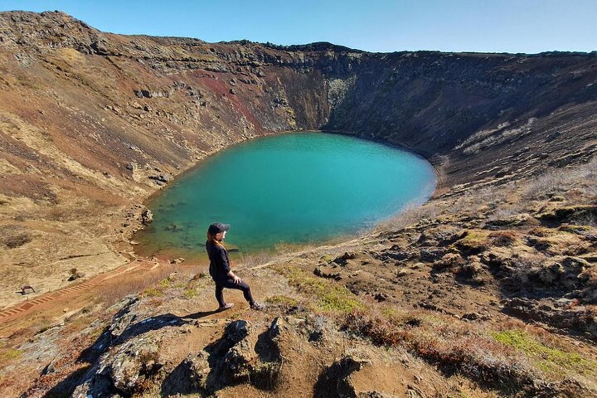 una persona in piedi in cima a una collina vicino a un lago