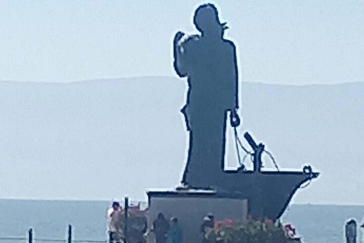 a statue of a man standing in front of the ocean