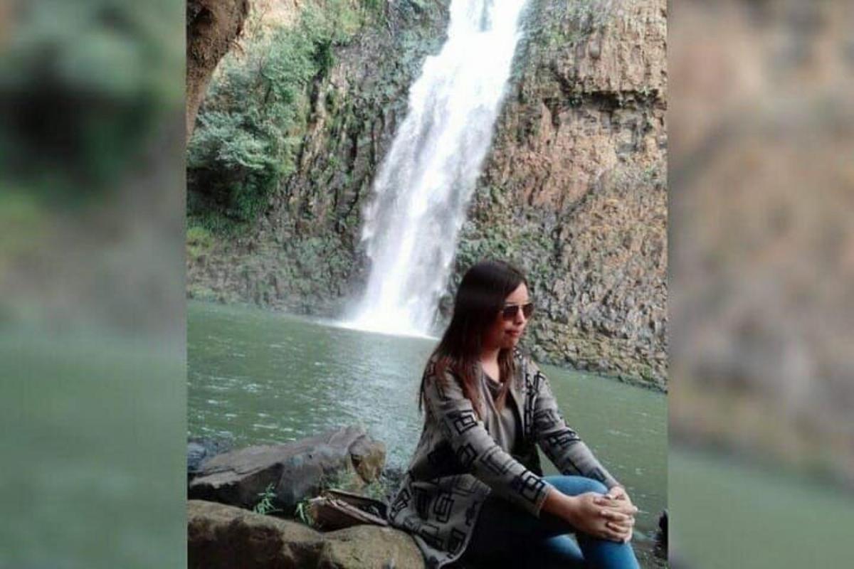 a woman sitting on a rock in front of a waterfall