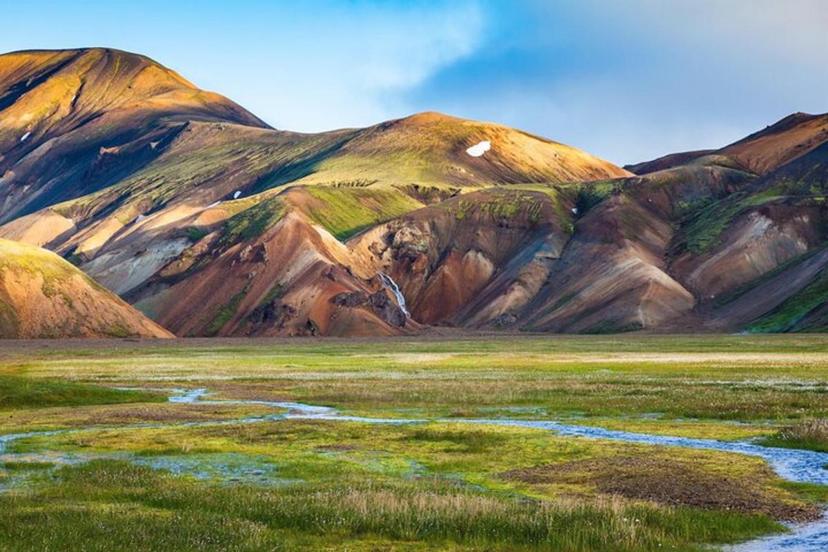 una cadena montañosa con un río en un campo