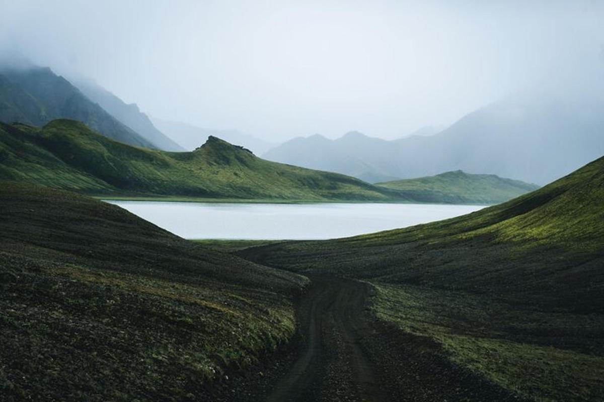 a dirt road leading to a lake in the mountains