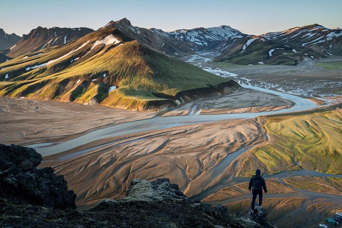 a man standing on top of a mountain overlooking a road