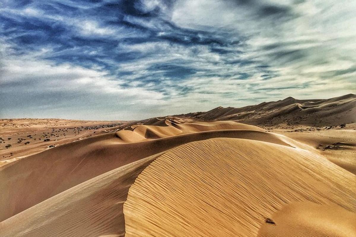 a desert with sand dunes and clouds in the sky