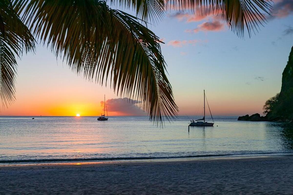 a beach with two boats in the water at sunset