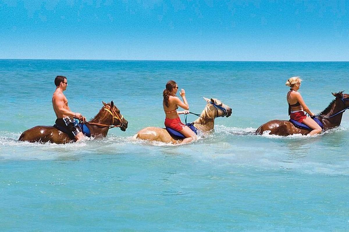um grupo de pessoas andando a cavalo no oceano