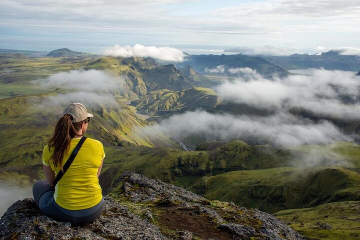 una donna seduta in cima a una montagna che guarda le nuvole