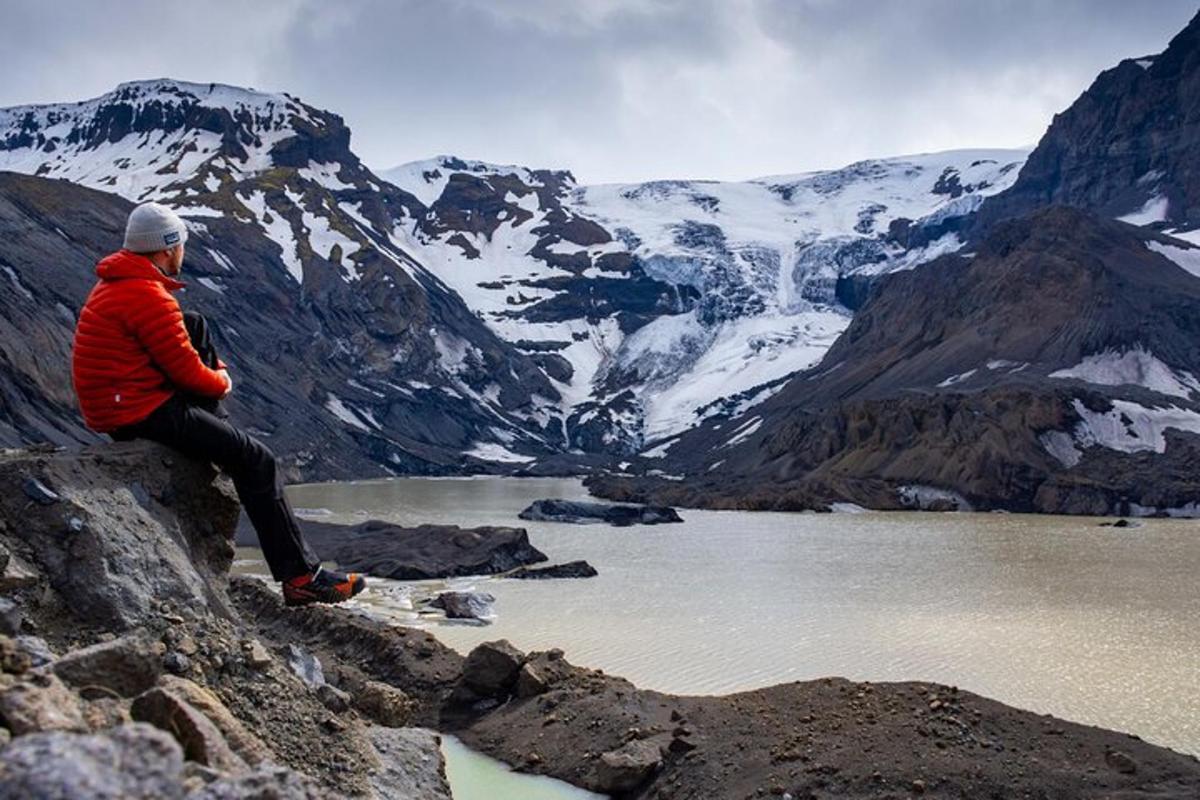 maður situr á fjallstindi með útsýni yfir vatn