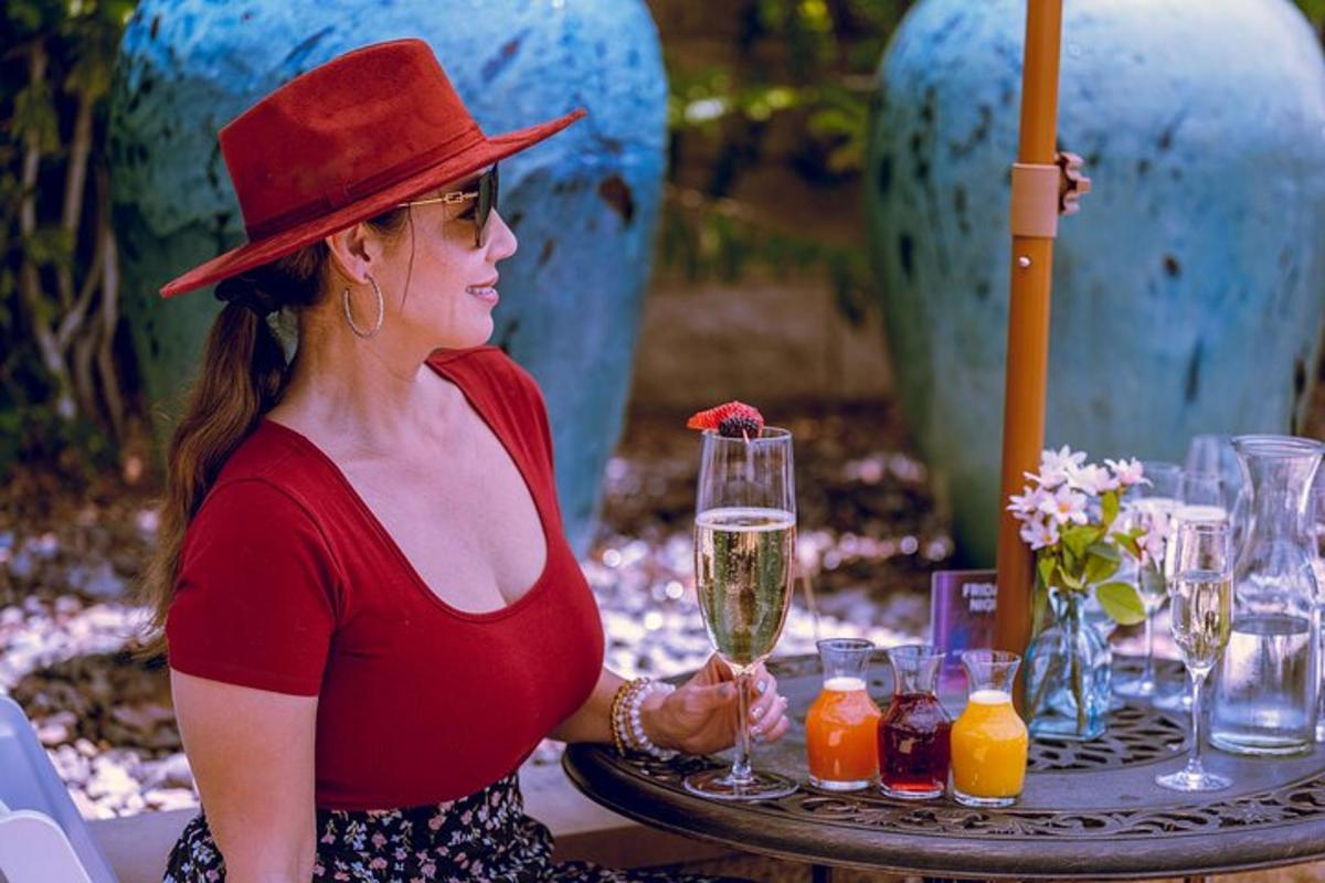 una donna con un cappello rosso che tiene in mano un bicchiere di vino