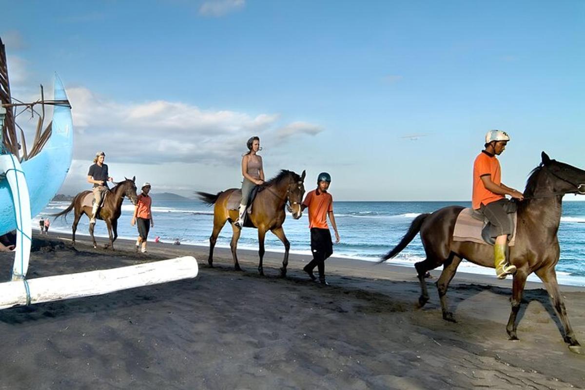 a group of people riding horses on the beach