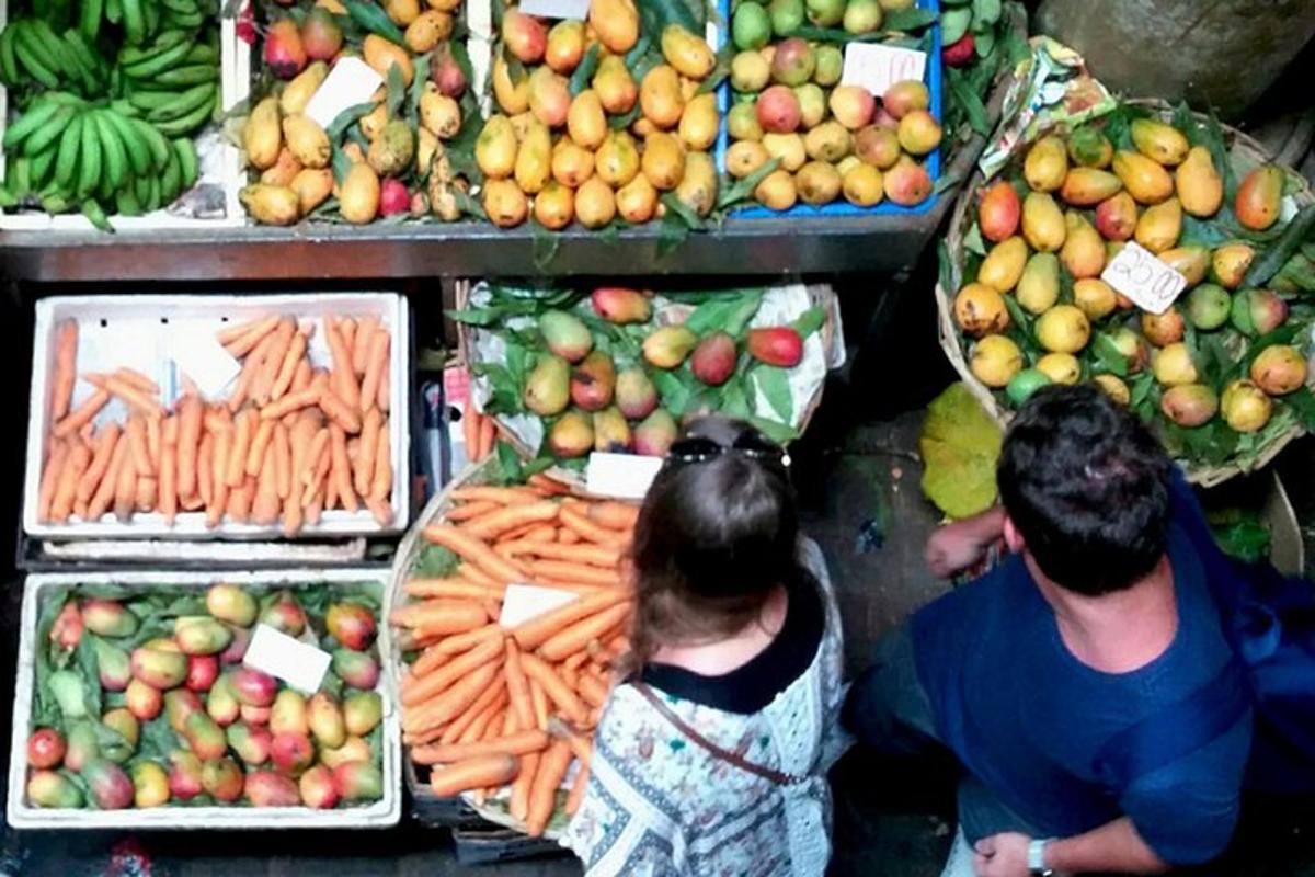 two people standing in front of a display of fruits and vegetables