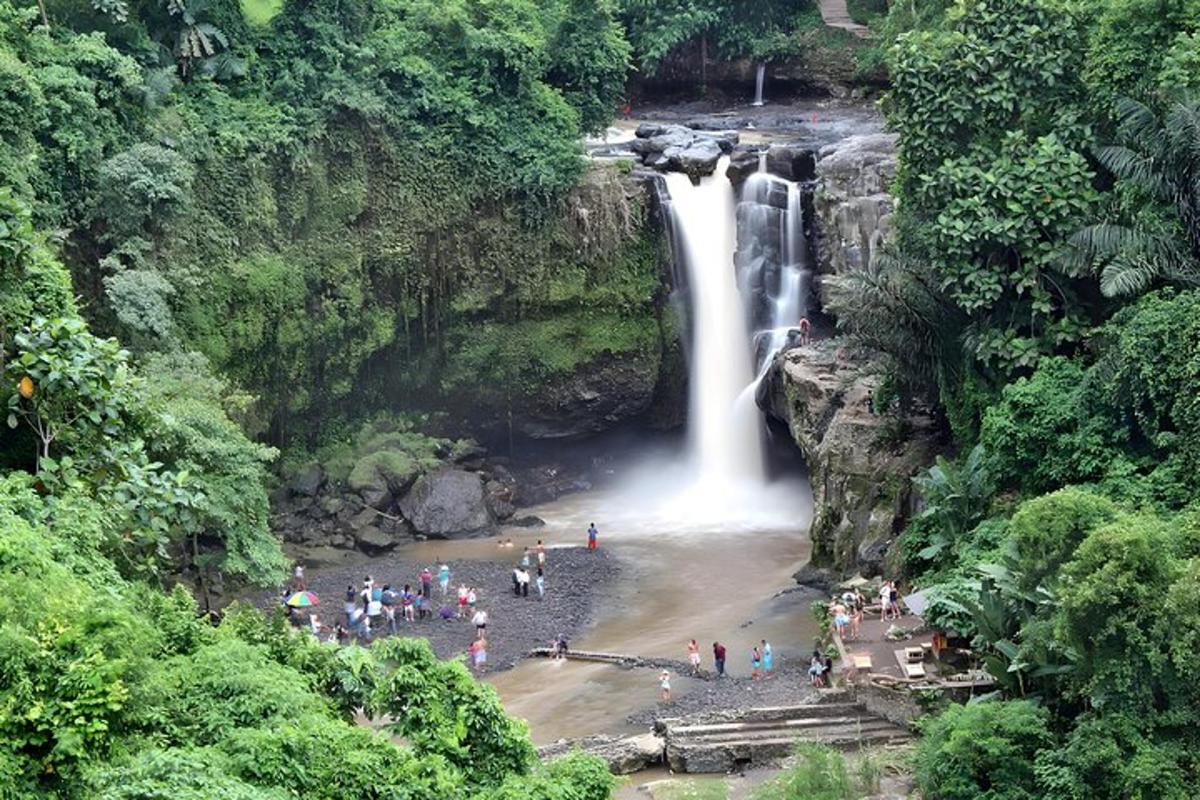 um grupo de pessoas em pé em frente a uma cachoeira