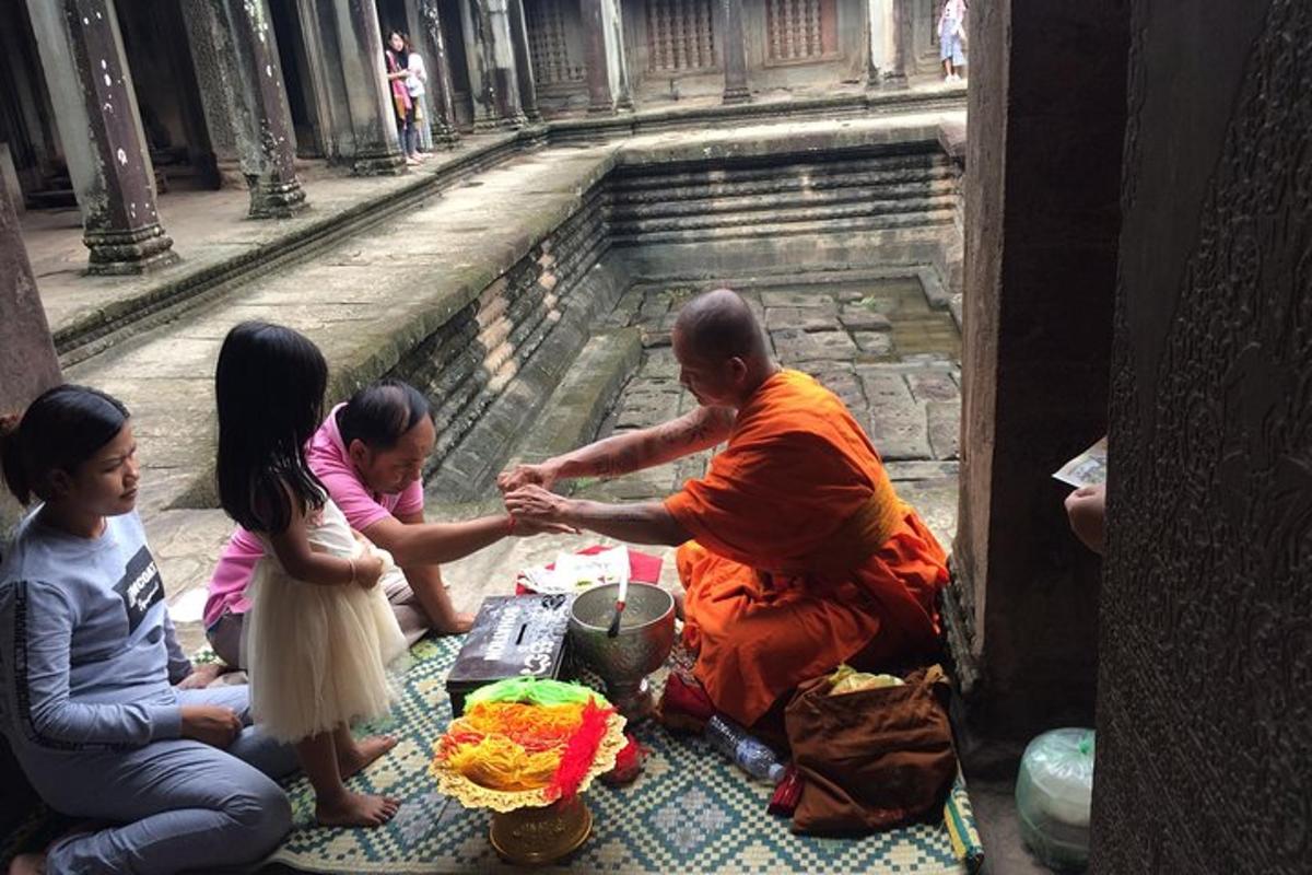 พระภิกษุรูปหนึ่งนั่งอยู่บนพื้นกับกลุ่มคน
