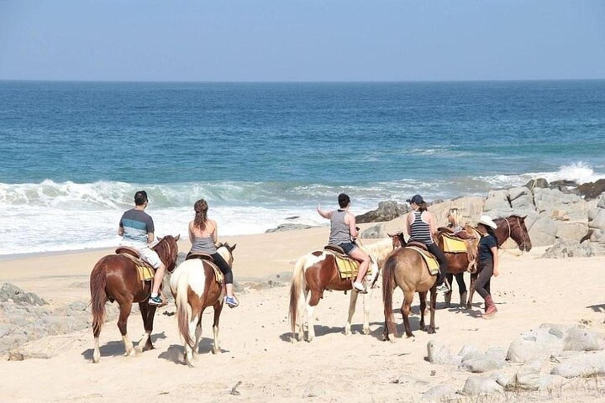 en gruppe mennesker, der rider på heste på stranden