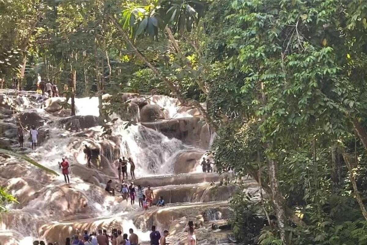 sekumpulan orang berdiri di hadapan air terjun