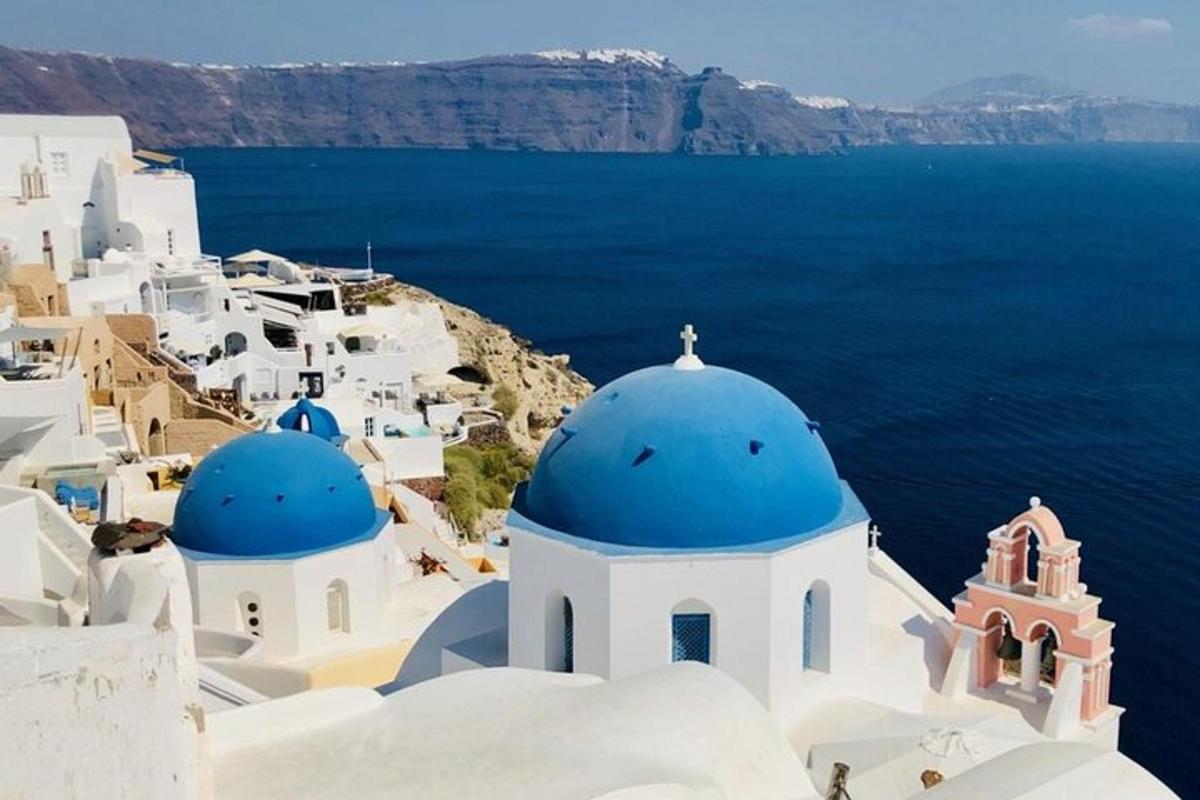 um grupo de edifícios brancos com cúpulas azuis e o oceano
