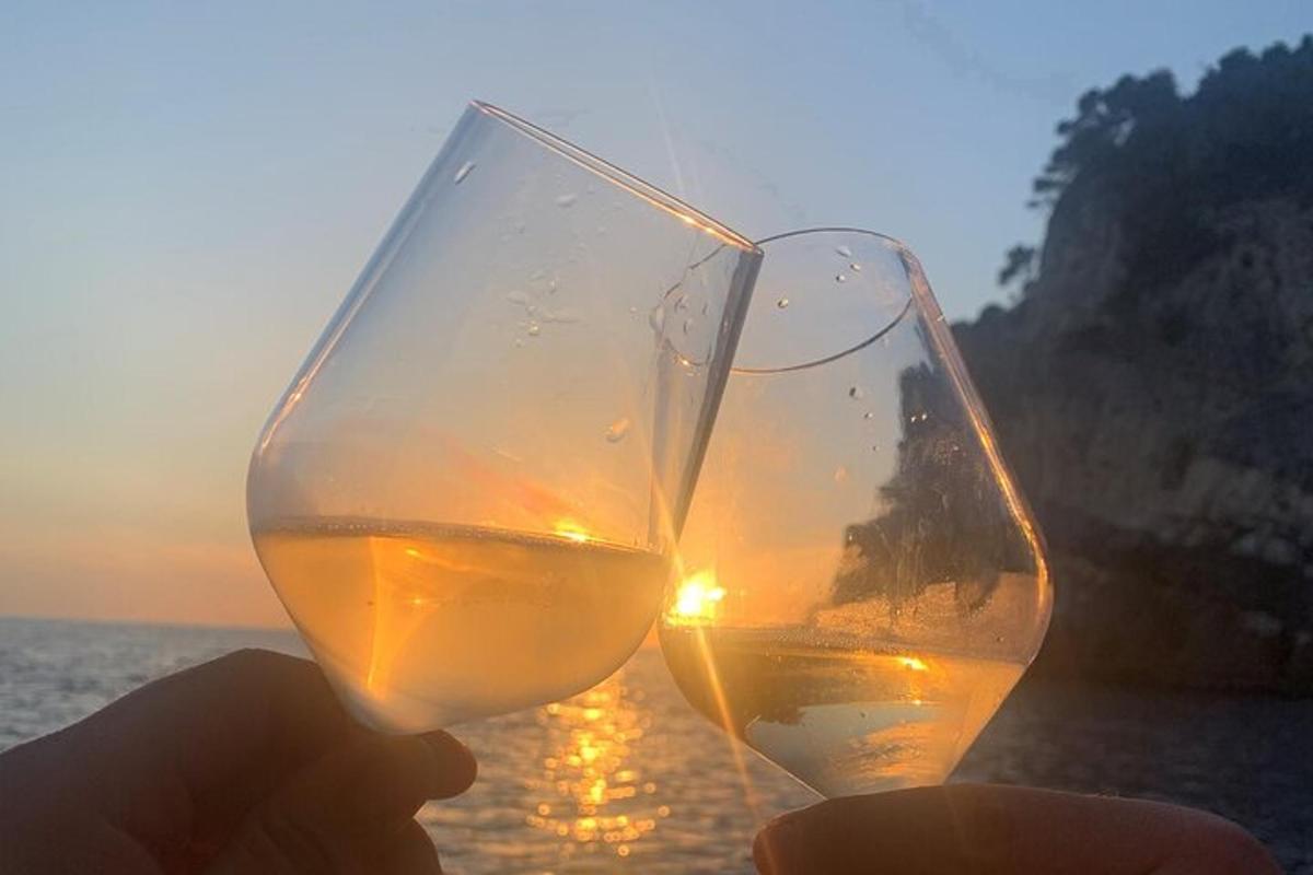 osoba držiaca pohár vína pred oceánom