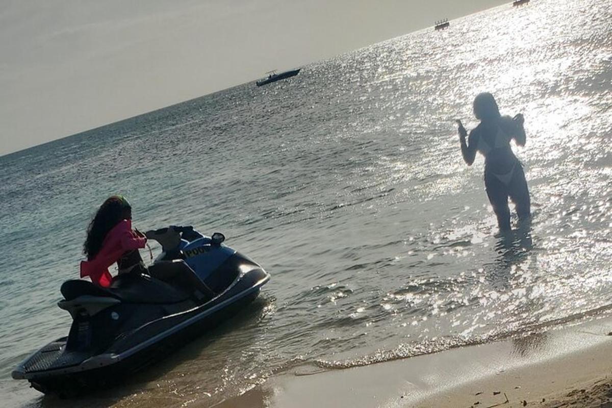 ženska, ki stoji v vodi poleg vodnega skuterja na plaži