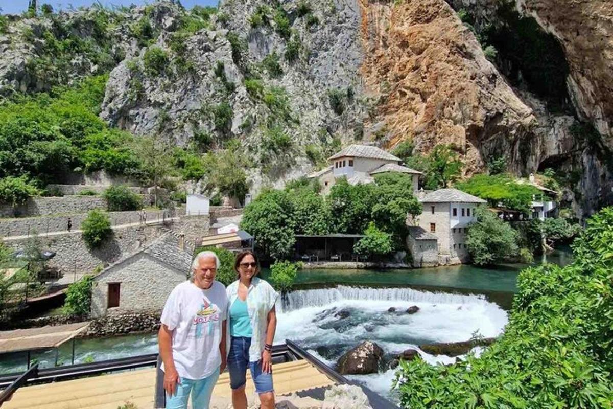 a man and woman standing in front of a waterfall