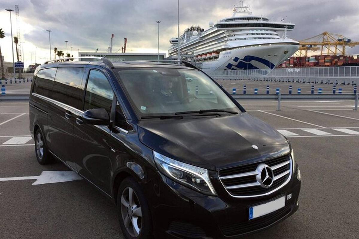 a black van parked in a parking lot with a cruise ship