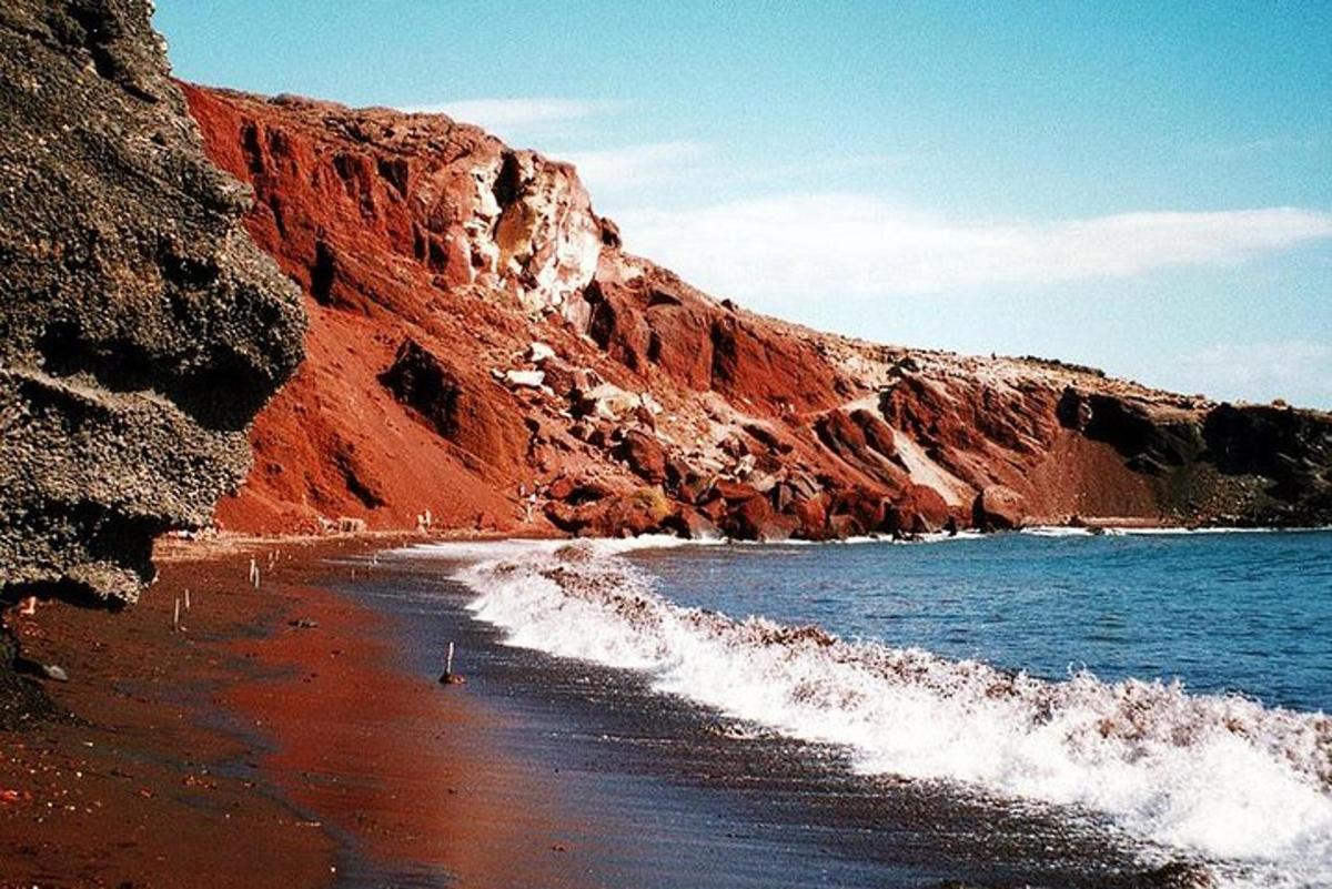 una spiaggia con una scogliera rossa e l'oceano