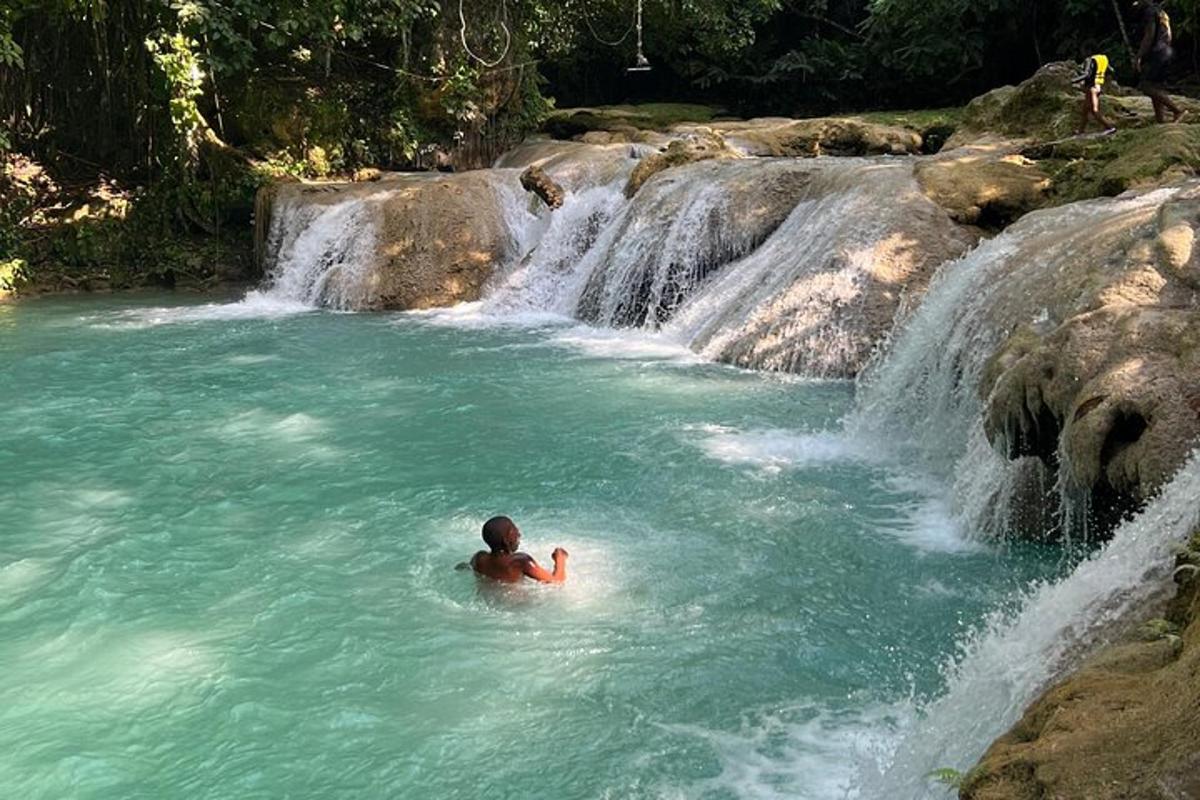 una persona nedant en una piscina davant d'una cascada